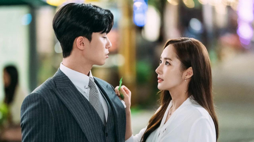 Foto de uma mulher e um homem, ambos sul-coreanos, se olhando. Imagem produzida durante as filmagens do K-drama.